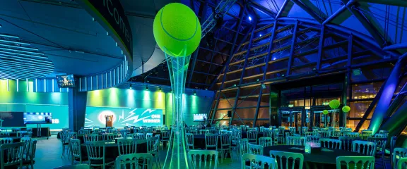 The atrium set up for a dinner event with a tennis theme. (c) Billie Jean King Cup 2022