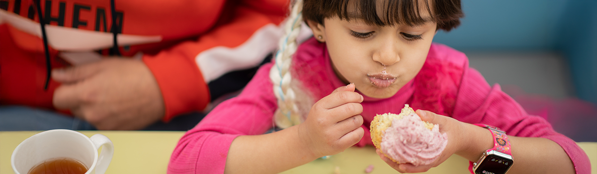 Child eating a pink icing topped cake