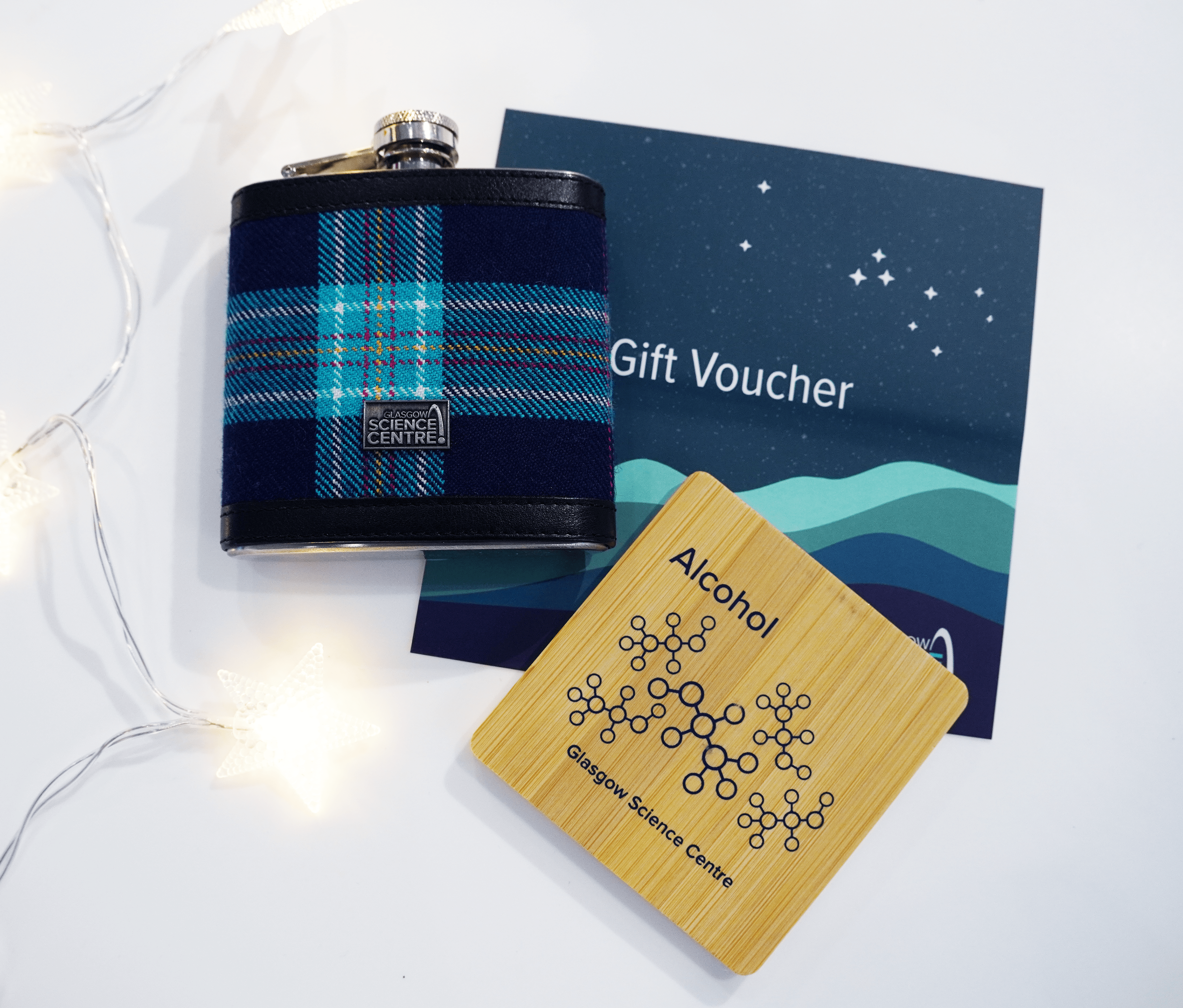 Gift voucher alongside a tartan hipflask and a coaster