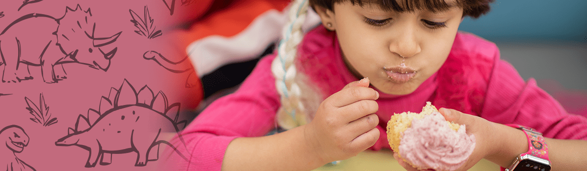 child eating a large pink cupcake