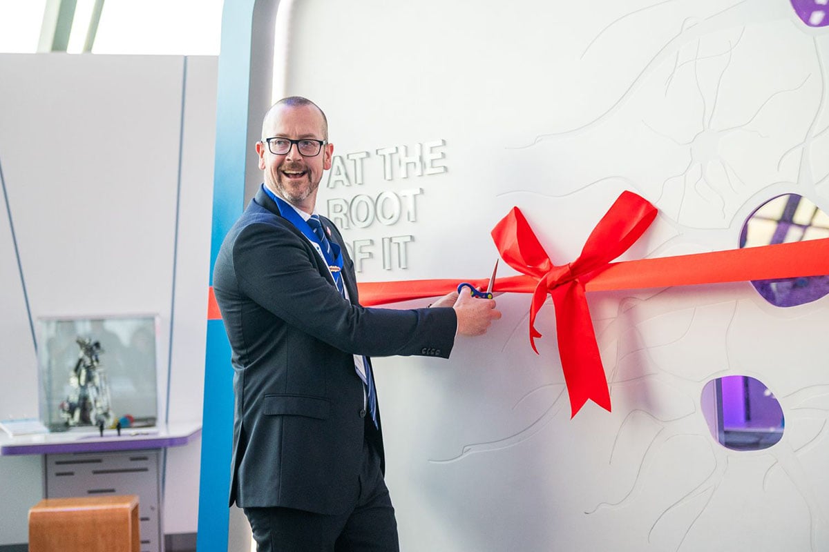 Professor William McLean cutting ribbon at exhibit