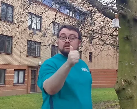 Presenter Sam beside a bird feeder on a tree