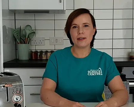 Alicia sits in the kitchen beside a toaster