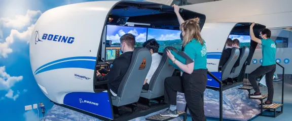 School students at the controls of flight simulators under the guiding instruction of flight crew.