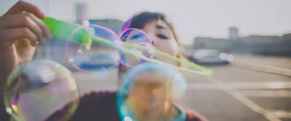 A woman blowing bubbles towards the viewer