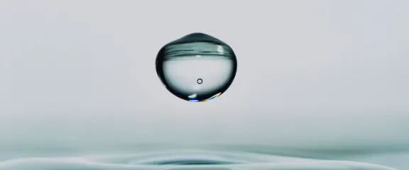 A water droplet falling towards a pool of water