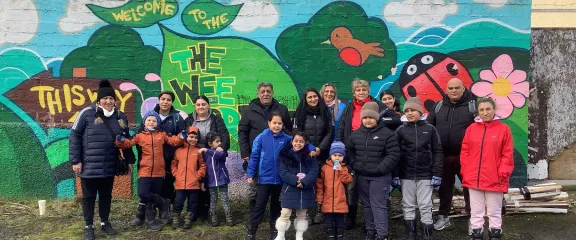 Participants in The Roots Project stand alongside the colourfully painted wall at the Wee Forest