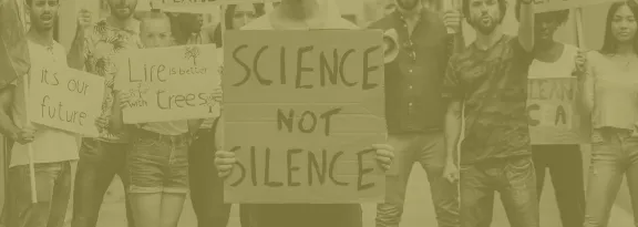 Activists protesting with one holding a sign 'science not silence'