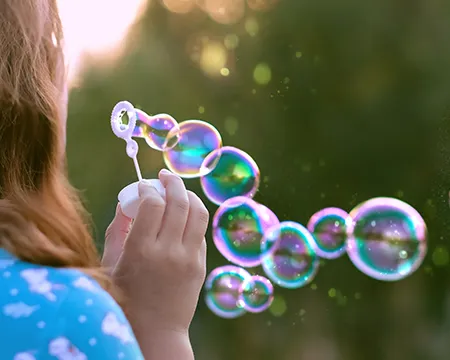 child blowing lots of bubbles through a bubble wand