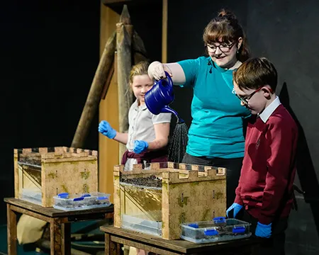 Pupils and a science communicator pour water into a model castle