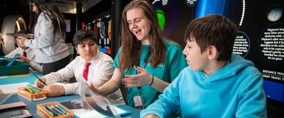 A science communicator and school pupils discuss an activity