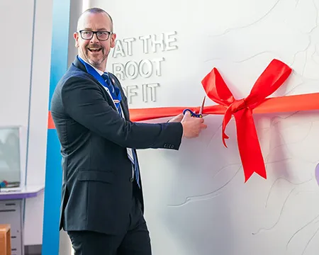 Professor William McLean cuts a red ribbon tied to launch the new endodontology exhibit at Glasgow Science Centre