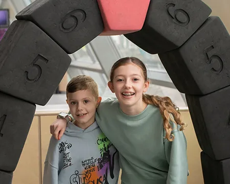 Two children playing with a bridge construction exhibit