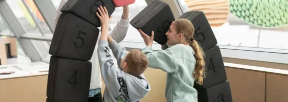 Two children playing with a bridge construction exhibit