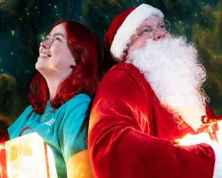 Woman and Santa hold onto glowing Christmas boxes in the Planetarium