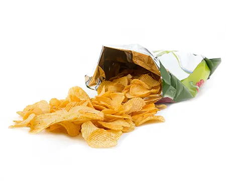 Crisps spill out from an open packet of crisps.