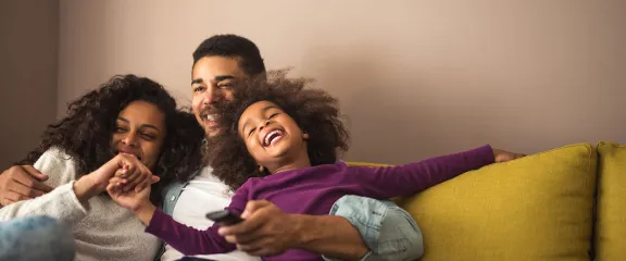 A young family laugh together on the sofa