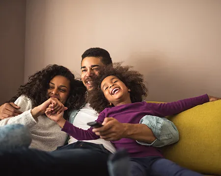 A young family laugh together on the sofa