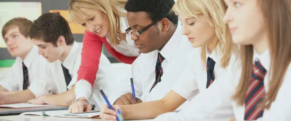 High school students in school uniform work at their desk