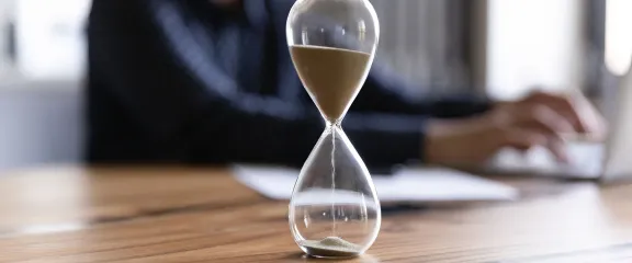 A glass sand timer on a wooden desk