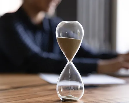 A glass sand timer on a wooden desk