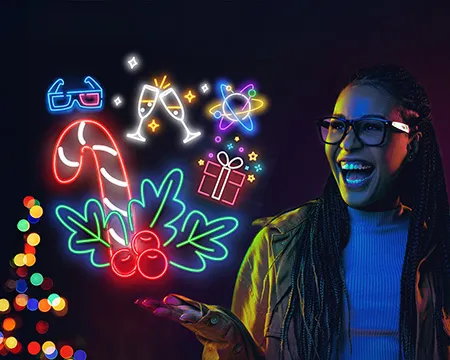 A young woman wearing glasses smiles in amazement at neon icons representing experiences at the science centre