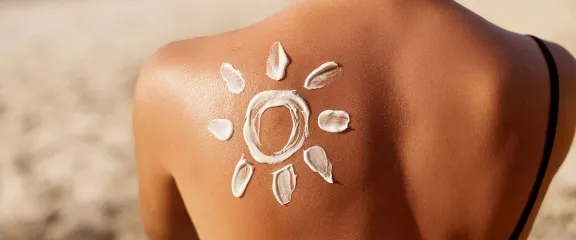 Sunscreen applied to a woman's back to create a sun and rays picture