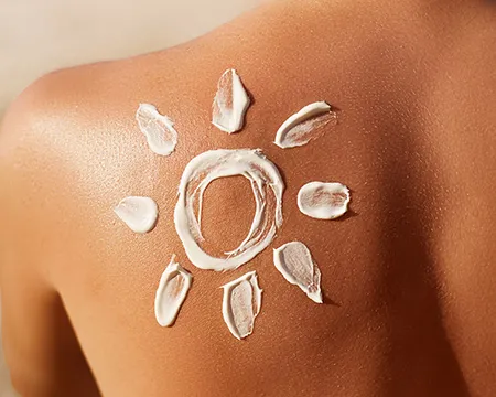 Sunscreen applied to a woman's back to create a sun and rays picture