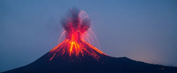 A volcano erupts against a dark sky