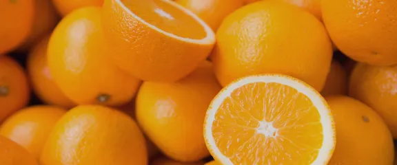 A pile of oranges with one sliced into two