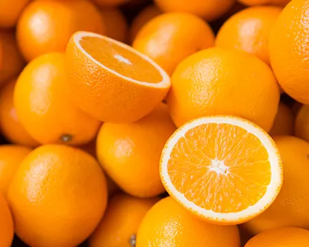 A pile of oranges with one sliced into two