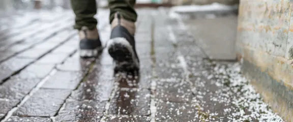 A man walks across a salted pavement free of ice