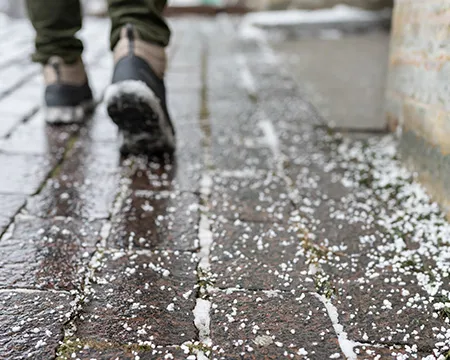 A man walks across a salted pavement free of ice