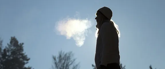 A woman breathes out into the cold air of winter