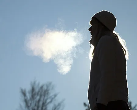 A woman breathes out into the cold air of winter