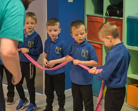 A line of school pupils hold a length of pink tubing to represent the process of digestion