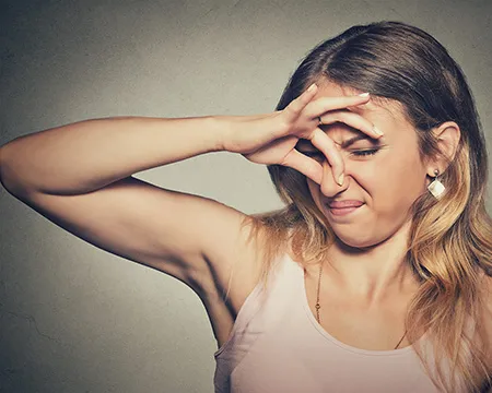 A woman hold her nose in disgust at a smell
