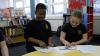 Two pupils use wooden cogs to complete a task at a table